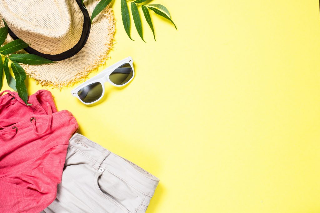 Woman summer cloth set - hat, top, shorts and sunglasses on yellow